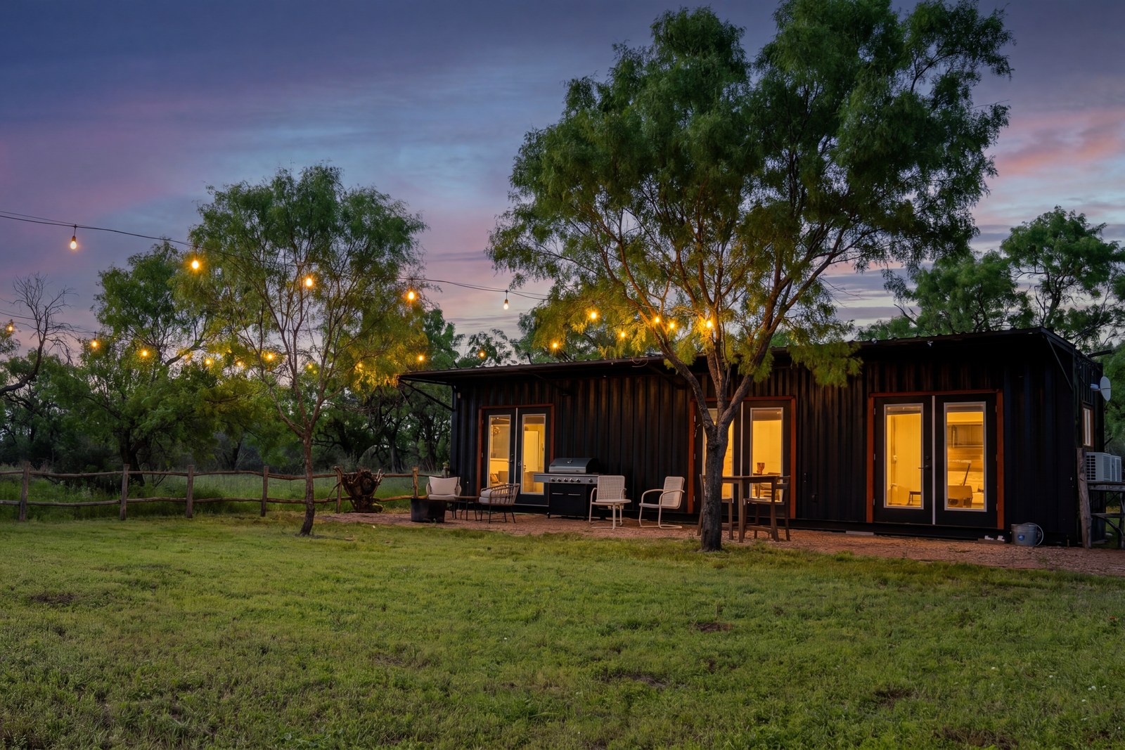 Nocona container cabin at twilight with patio dining and string lights